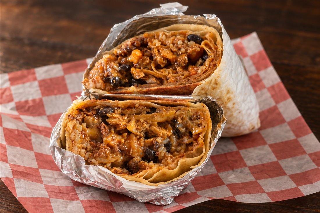 A cut Cynful Taste burrito with rice, beans and savory filling